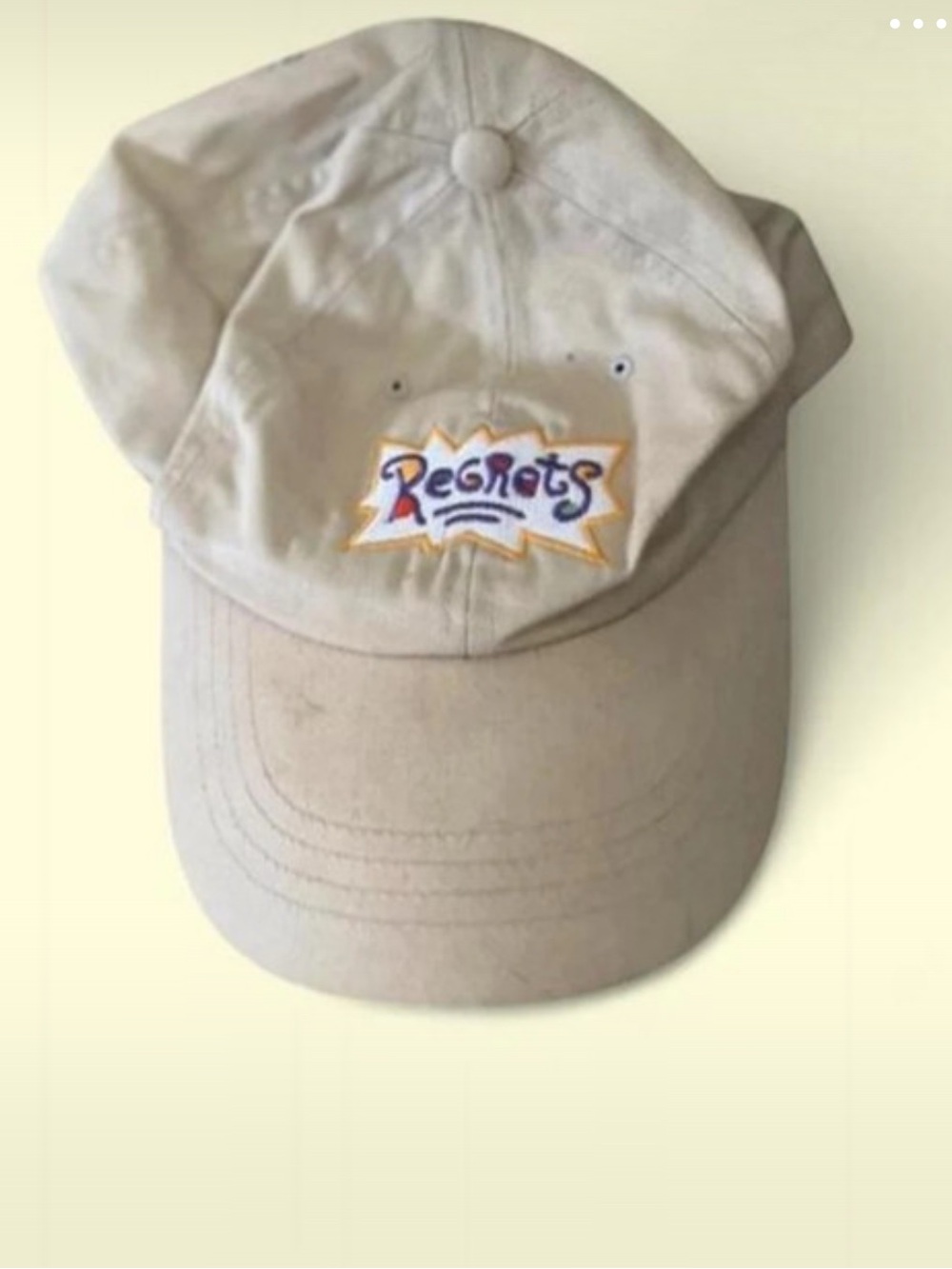 Beige “No Regrats” dad hat with colorful Rugrats-inspired embroidered graphic